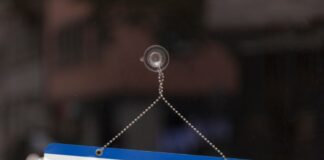 The First Roles You Need To Fill at Your Growing Startup A small blue-and-white sign suction-cupped to a glass surface. The sign has text reading "Help Wanted" on it.