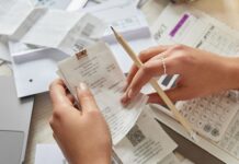 How To Identify and Eliminate Hidden Business Expenses A business owner sits at the table with a bunch of receipts all over as they audit their business expenses.