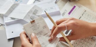 A business owner sits at the table with a bunch of receipts all over as they audit their business expenses.