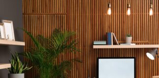 Top Home Office Upgrades for a Growing Business A home office features a wooden slat accent wall, a desk with a computer, a tan office chair, and several potted plants.