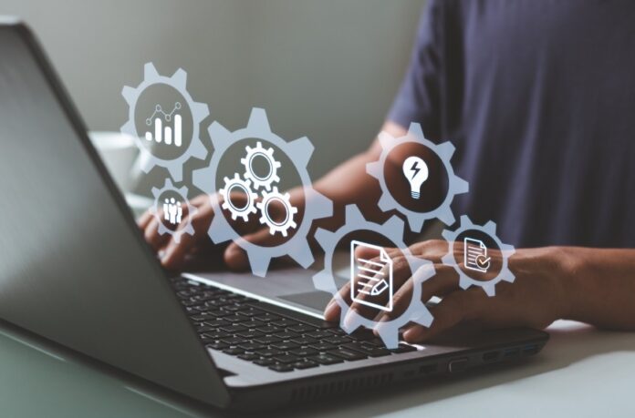 A person uses a laptop with digital icons representing automation, workflows, and business system management tools.